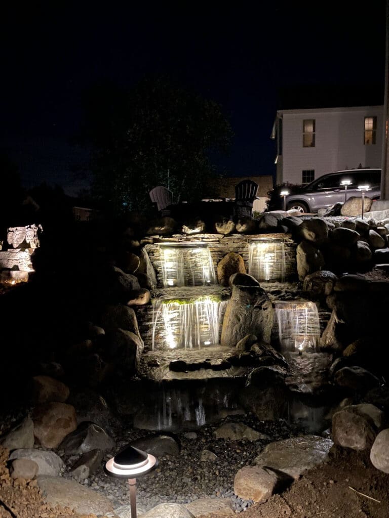 a lit up waterfall in a backyard
